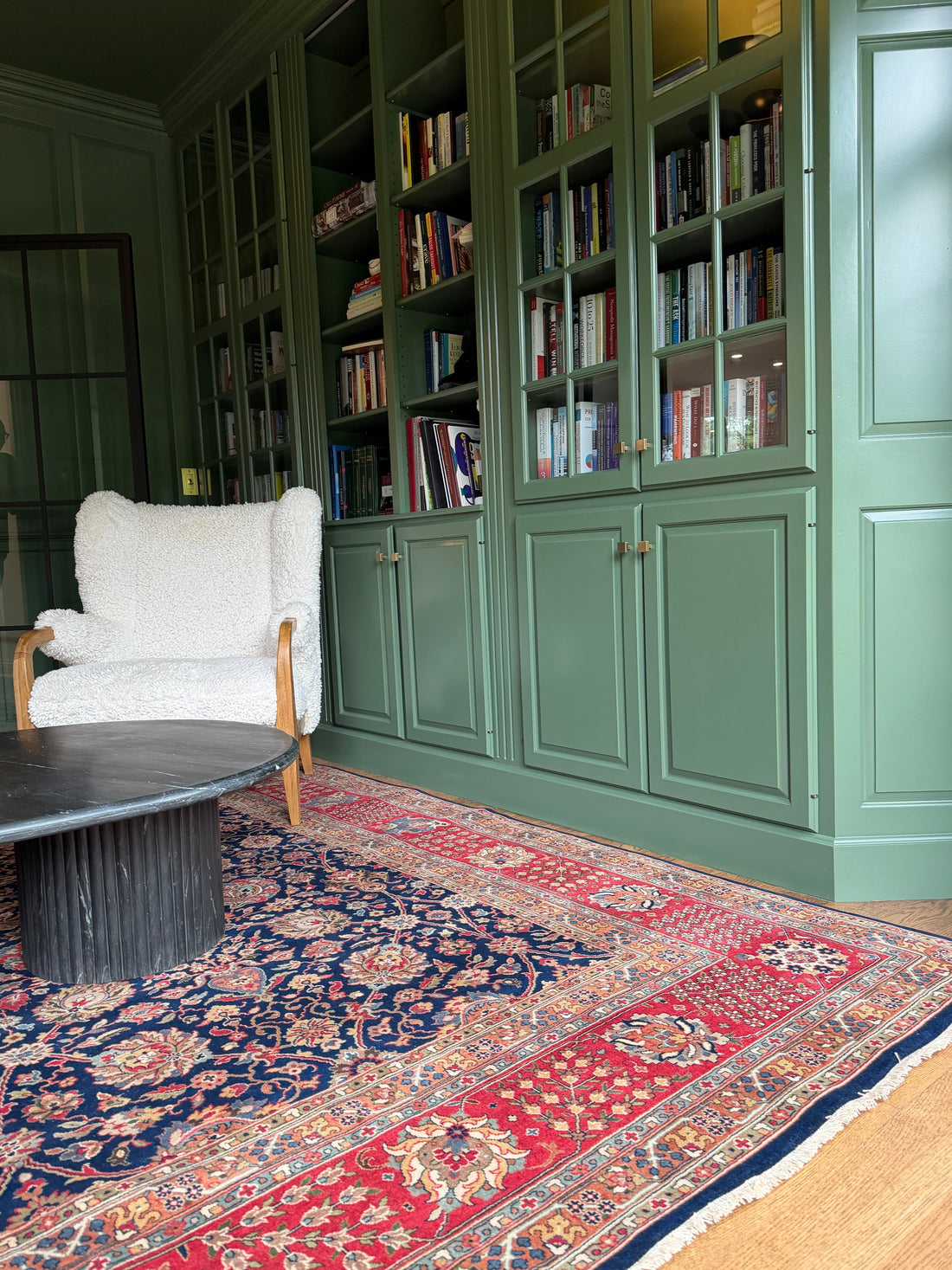 Navy handmade rug in a green-panelled library