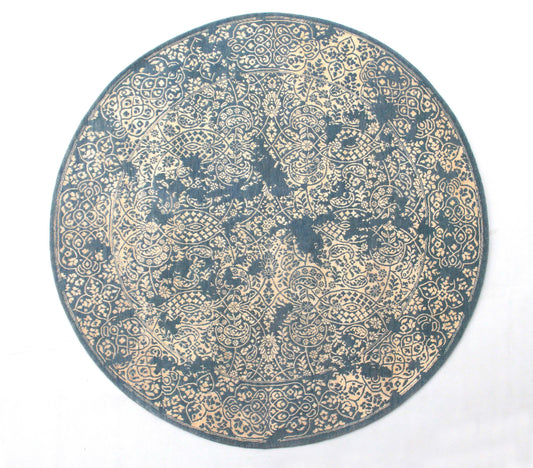 A round, hand-knotted wool and silk rug with a paisley design in blue and beige colors.